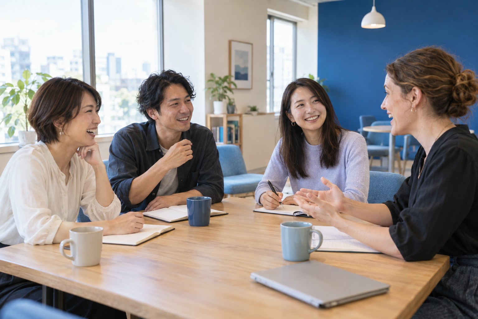 明るい教室で会話を楽しむ大人の学習者と講師。イメージ。